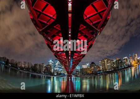 Pedonale ponte di pace e il centro cittadino di Calgary riflettente nel Fiume Bow di notte. Calgary, Alberta, Canada. Foto Stock