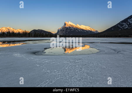 Mount Rundle riflettendo in una piscina sulla congelati laghi Vermiglio al tramonto nel Parco Nazionale di Banff, Alberta, Canada. Foto Stock