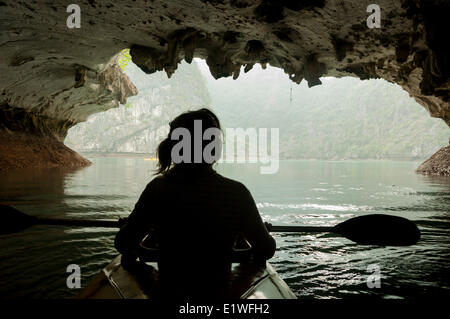 Il kayak attraverso un arco di roccia in Lan Ha Bay, Vietnam Foto Stock
