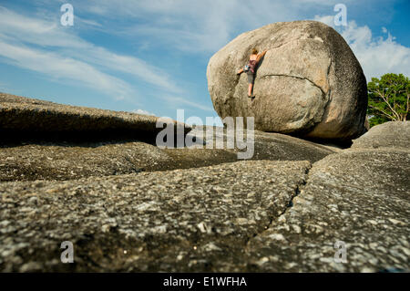 Una giovane donna bouldering vicino a Kata Beach, Phuket, Tailandia Foto Stock