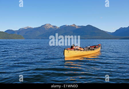 Un canoer incline a riposo nella sua canoa dopo una dura giornata di pala sul lago Murtle, Grey Park, British Columbia, Canada, Darrel G Foto Stock