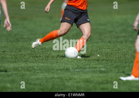 Ragazza giovane calciare il pallone mentre giocano a calcio. Calgary, Alberta, Canada Foto Stock