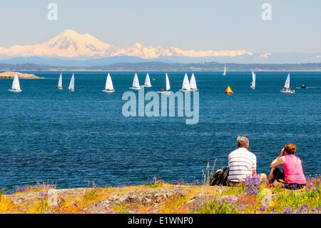 Un paio di guardare il laser barche a vela corse off punto di bestiame in Oak Bay in Victoria, BC. Foto Stock