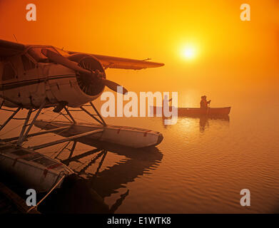 Giovane canoa in early morning mist vicino float plane dock, Manitoba, Canada Foto Stock