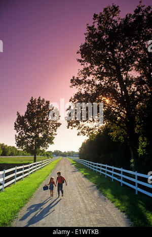 Due bambini correre giù per una strada di campagna sulla loro strada per la scuola, nei pressi del Grande Pointe, Manitoba, Canada Foto Stock