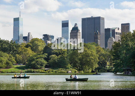 Lussureggiante parco centrale fissato contro la città di New York grattacieli. In primo piano è il lago dove parkgoes possono noleggiare barche a remi relax Foto Stock