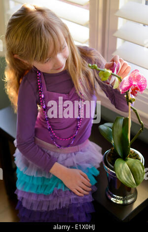 Ragazza giovane appeso accanto a un'orchidea Foto Stock