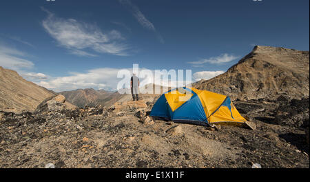 Un uomo in piedi che si affacciava sulle montagne dello Yukon gamma costiera vicino a Carcross, Yukon. Nuvole di tempesta stanno costruendo su th Foto Stock