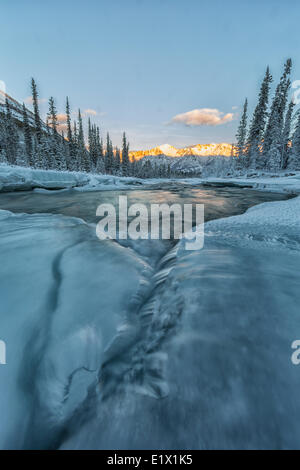 Gli ultimi raggi di sole hit dorsale grigio come Wheaton fiume scorre verso il lago di Bennett, Yukon. Foto Stock