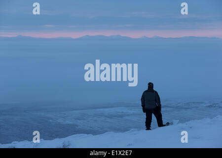 Persona in piedi sulla cima del monte Corvo mentre copre la vallata sottostante, Yukon settentrionale. Foto Stock