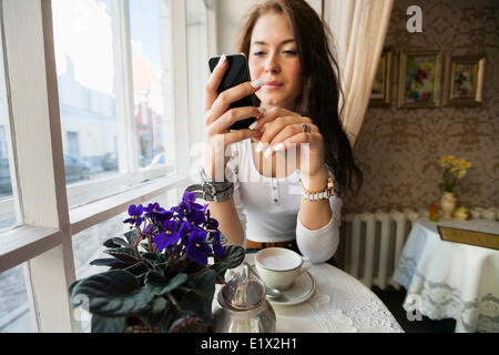 Giovane donna utilizzando smart phone al cafe tabella