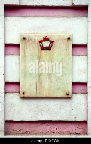 Lastra di granito con il simbolo comunista in rosa vecchio muro Foto Stock
