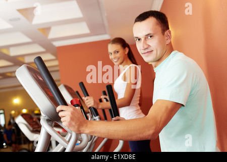 Ritratto di giovane uomo della formazione su speciali attrezzature sportive in palestra Foto Stock