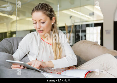 Giovane imprenditrice utilizzando tablet PC in ufficio Foto Stock