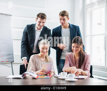 Happy young business persone utilizzando tablet PC alla scrivania in ufficio Foto Stock