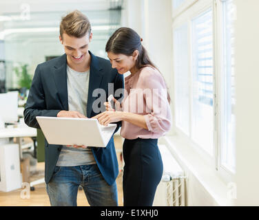 Giovane imprenditore e imprenditrice utilizzando computer portatile in ufficio Foto Stock