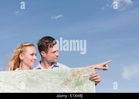 Giovane Azienda mappa mentre donna rivolto lontano contro sky Foto Stock