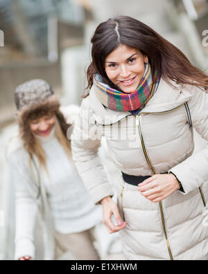 Sorridente giovane donna a salire le scale con un amico all'aperto Foto Stock
