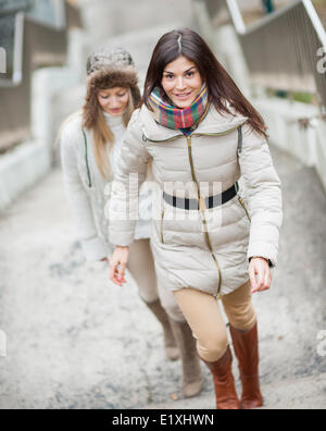 Per tutta la lunghezza della bella donna a salire le scale con un amico all'aperto Foto Stock