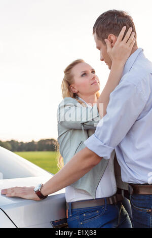 Vista laterale della romantica coppia giovane in auto a campagna Foto Stock