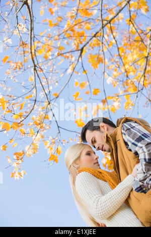 Basso angolo vista del giovane costeggiata contro autumn tree Foto Stock