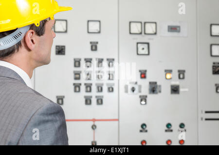 Vista posteriore del giovane maschio esaminando supervisore sala di controllo nell'industria Foto Stock