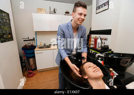 Sorridente parrucchiere maschio femmina di lavaggio del cliente in capelli salon Foto Stock