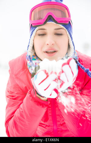 Giovane donna indossa cappotto invernale lavori di soffiaggio della neve all'aperto Foto Stock