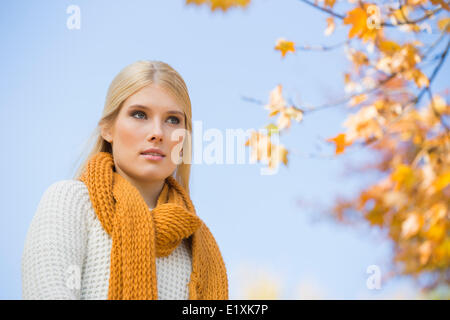 Basso angolo di vista riflessivo giovane donna contro sky Foto Stock