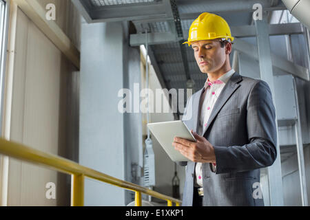 Giovane imprenditore utilizzando computer tablet nell'industria Foto Stock