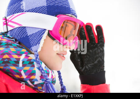 Vista laterale di close-up di bella giovane donna in maschere da sci che guarda lontano Foto Stock