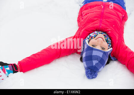 Ritratto di giovane sorridente donna sdraiata sulla neve