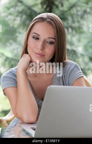 Rilassata giovane donna utilizzando laptop all'aperto Foto Stock