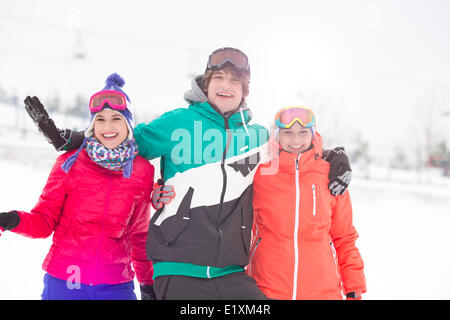 Ritratto di giovane uomo con amici di sesso femminile per godere nella neve Foto Stock