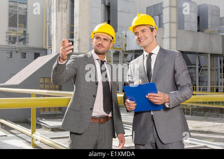 Giovani ingegneri maschio con appunti a discutere al di fuori dell'industria Foto Stock