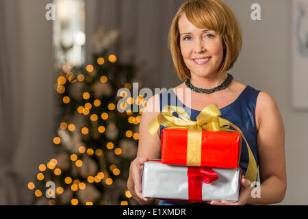 Ritratto di donna sorridente tenendo i regali di Natale a casa Foto Stock