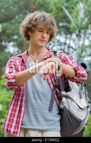 Giovane maschio escursionista controllando il tempo in foresta Foto Stock