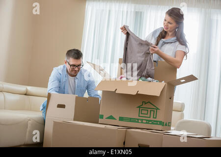 Mid-adulto giovane disimballaggio scatole di cartone nella nuova casa Foto Stock