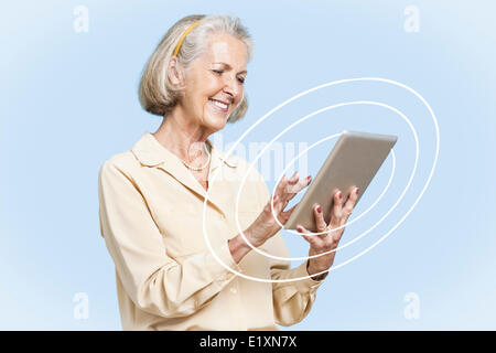 Felice senior imprenditrice utilizzando tablet PC contro il cielo blu chiaro Foto Stock
