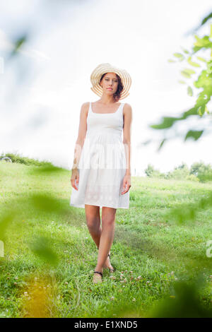 Ritratto di giovane donna in sundress e hat passeggiate nel parco Foto Stock