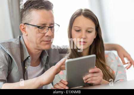 Padre e figlia con tavoletta digitale in casa Foto Stock