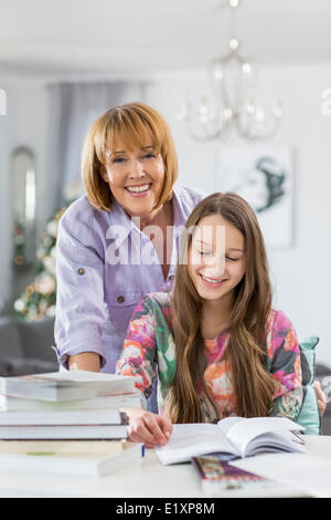 Ritratto di felice madre aiutare mia figlia a fare i compiti a tavola Foto Stock