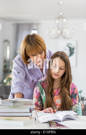 Madre figlia di guida nel fare i compiti a tavola Foto Stock