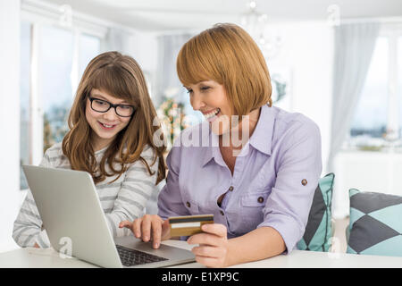 Allegro madre e figlia lo shopping online a casa durante il periodo di Natale Foto Stock