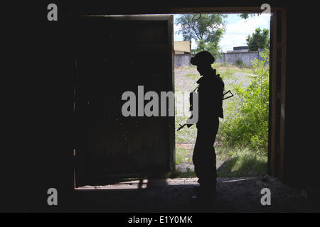 Donbas, Donetsk, Ucraina. Decimo Giugno, 2014. Soldato resta davanti alla forata con proiettili porta del garage dopo lo scontro con pro-russo i terroristi in corrispondenza di un punto di controllo vicino a Slaviansk. Esercito ucraino continua a mantenere il pro-russo terroristi sotto assedio durante l ATO in Donbas. Le operazioni militari si è concentrato sempre di più sul Slaviansk, una città di 130.000 che è stata controllata a partire dal mese di aprile da mascherata, camouflage-placcati militanti assalto brandendo fucili e granate-lanciatori che si oppongono alla regola centrale di Kiev. Credito: Sergii Kharchenko/NurPhoto/ZUMAPRESS.com/Alamy Live News Foto Stock