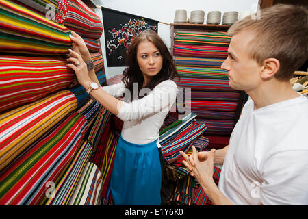 Addetto alle vendite femmina ad assistere l'uomo nel negozio TESSILE Foto Stock