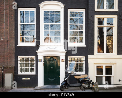 AMSTERDAM, Paesi Bassi - 19 Marzo 2014: nero scooter Vespa parcheggiata sorge nei pressi della vecchia casa vivente in Amsterdam Foto Stock