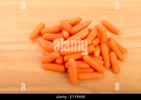 Un mucchio di pelati carotine su una tavola di legno Foto Stock