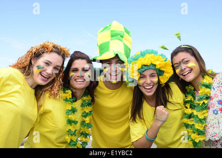 Gruppo di felice il brasiliano gli appassionati di calcio per commemorare la vittoria con la bandiera brasiliana in background Foto Stock