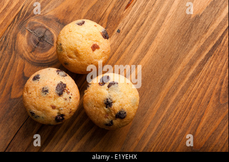 Tre piccoli muffin con scaglie di cioccolato su un tavolo di legno Foto Stock